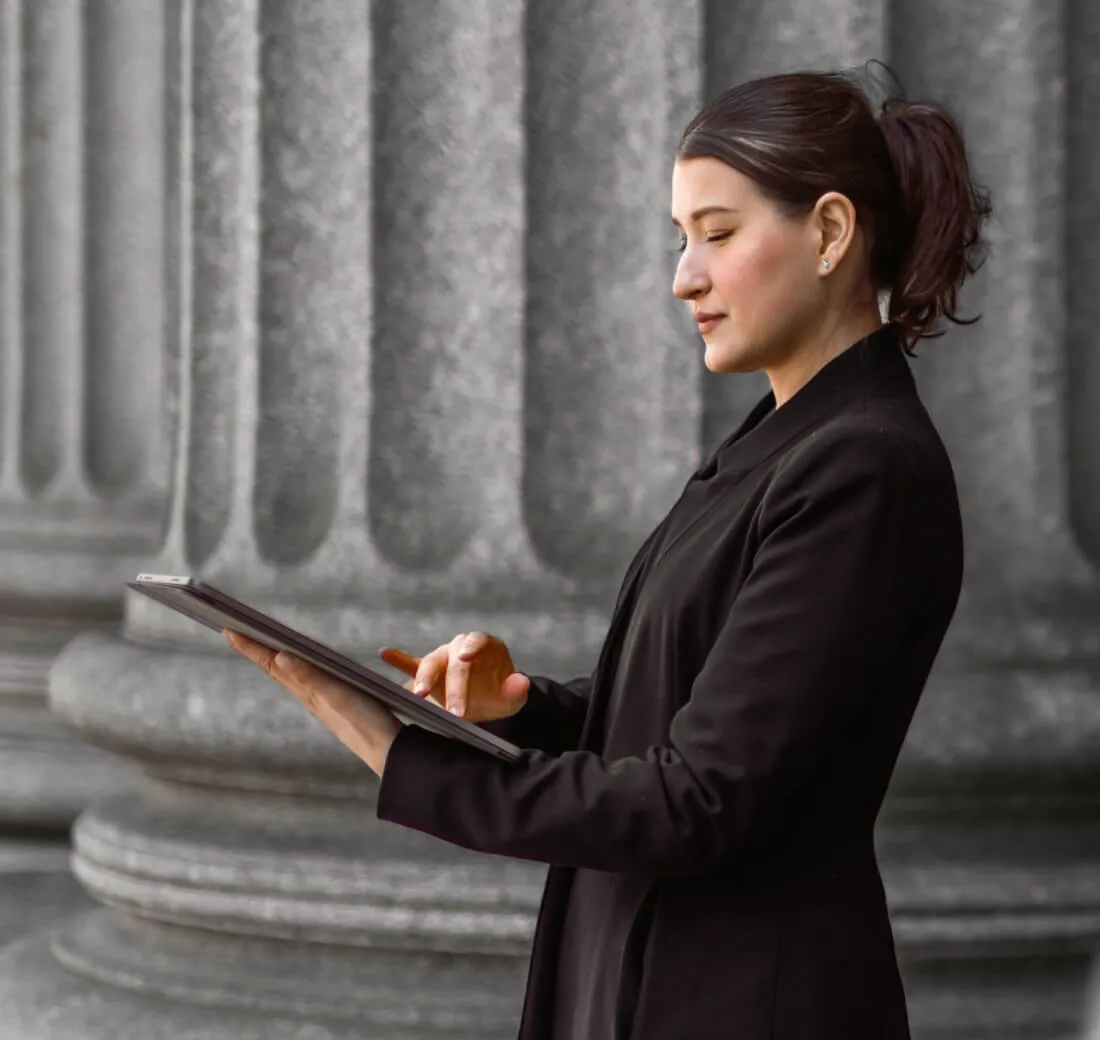 Une femme vérifie sa tablette devant un bâtiment du gouvernement