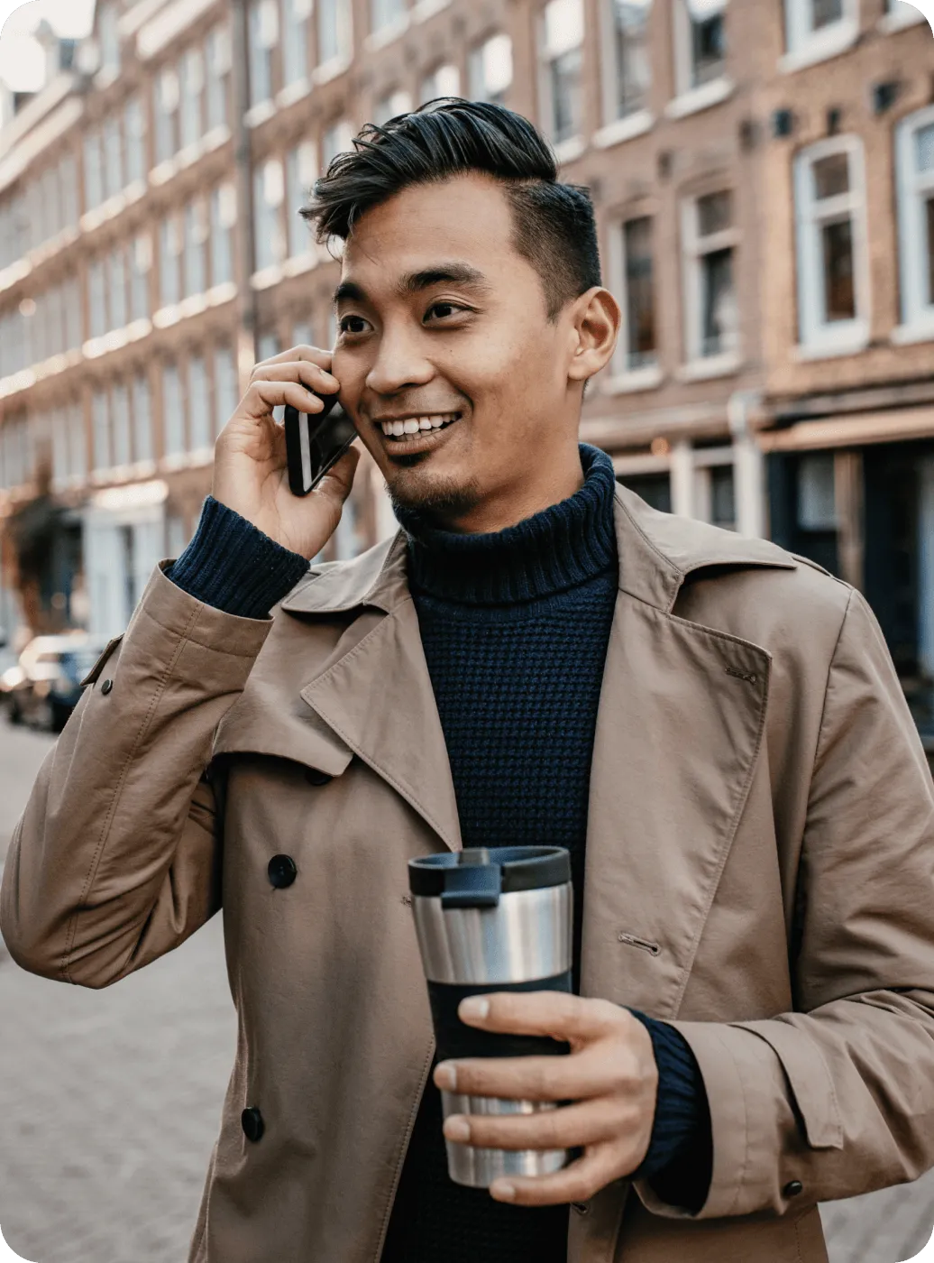 Un homme prenant un appel dehors avec un verre à la main