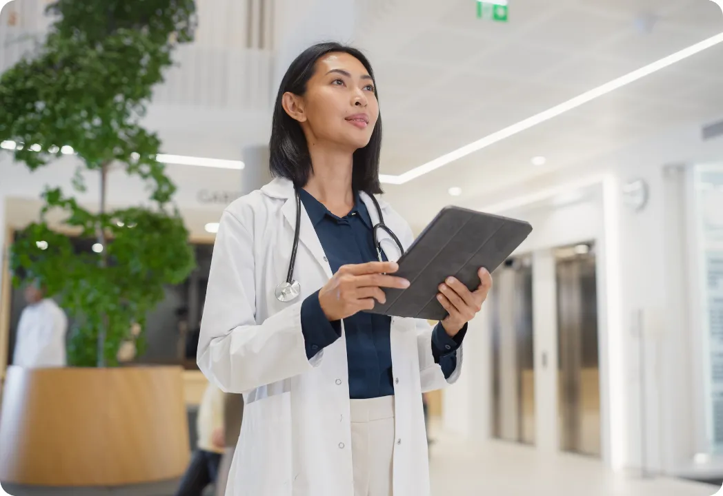 Female doctor looking into the distance while holding an iPad